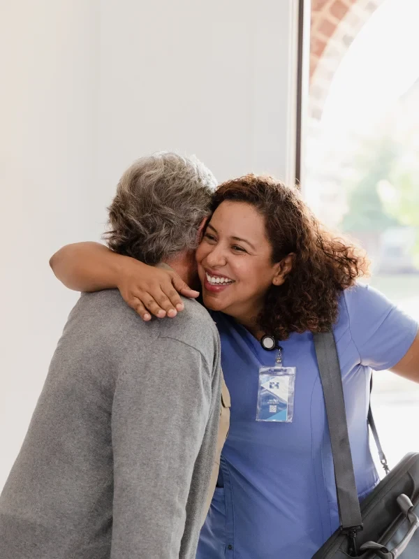 Caregiver hugging an elderly man with a warm, comforting gesture, showing compassion and support in hospice care.
