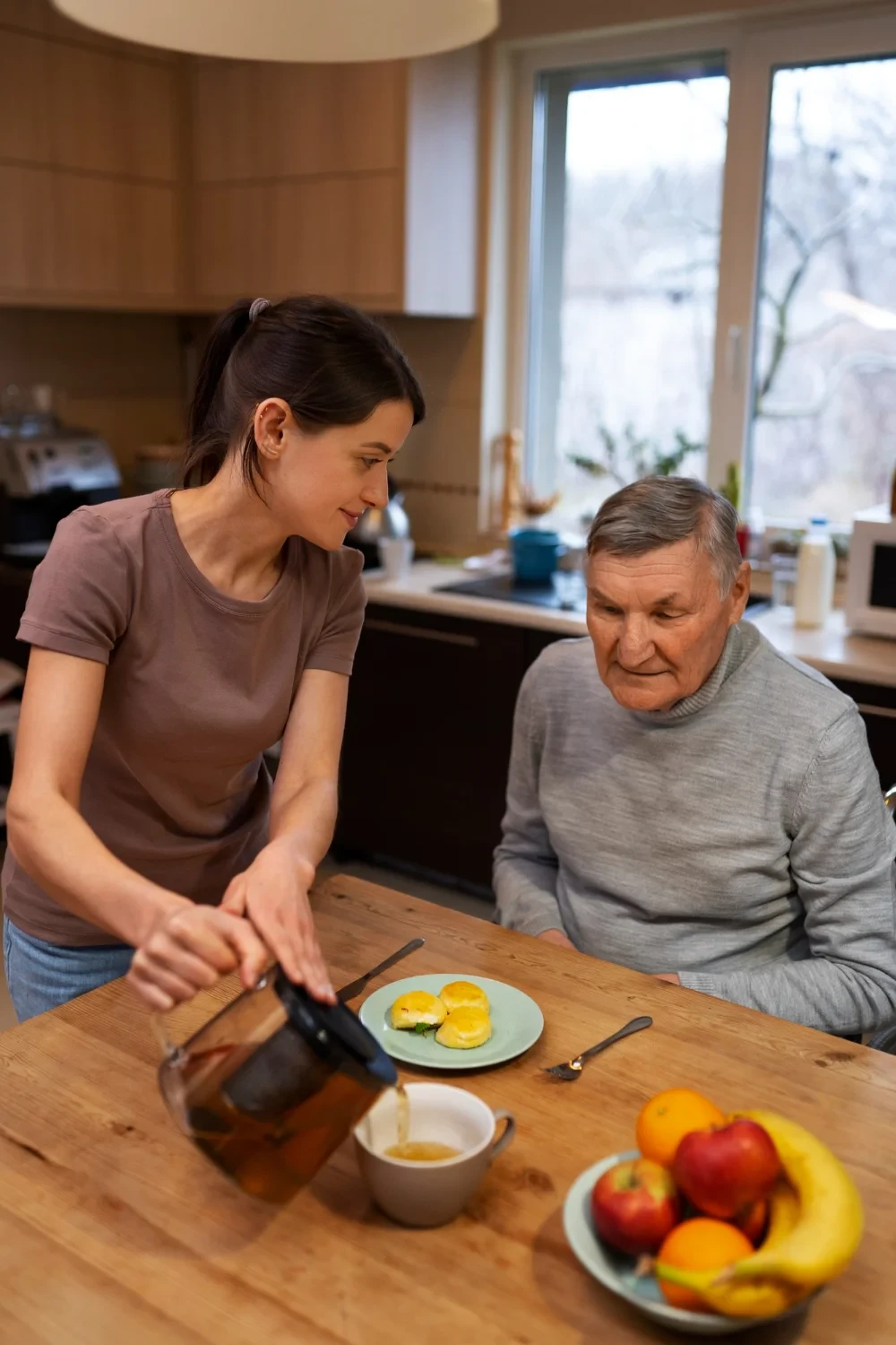 A caregiver serving breakfast to an elderly man, with a focus on nutritious meals and companionship.