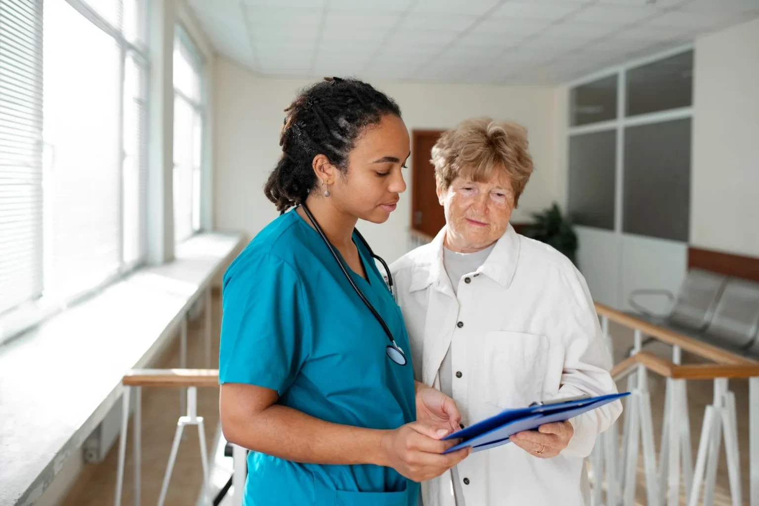 A nurse and elderly woman reviewing medical information together, discussing specialized care for chronic conditions.