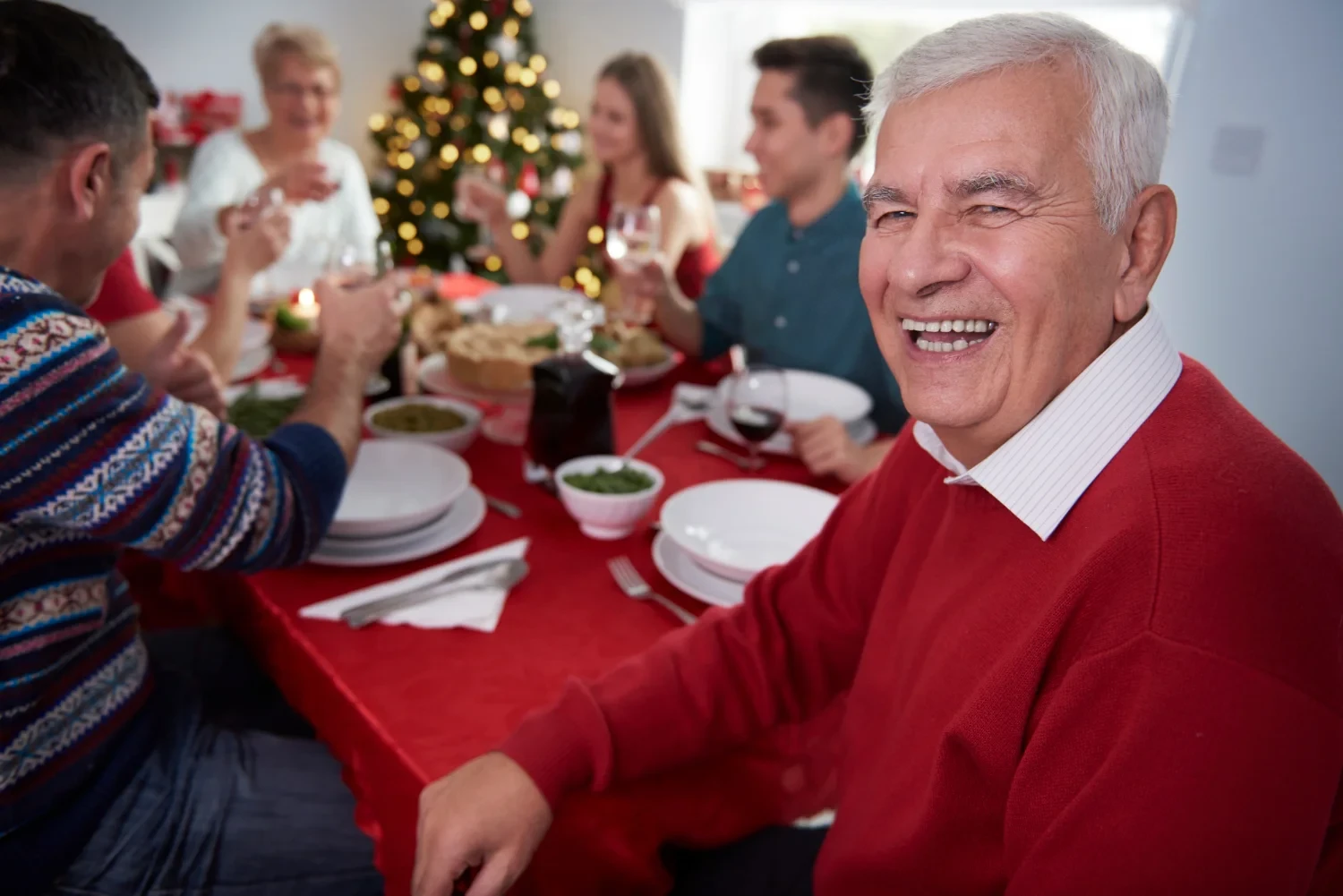 Elderly residents celebrating with food and drinks in a joyful, festive atmosphere at an assisted living facility.
