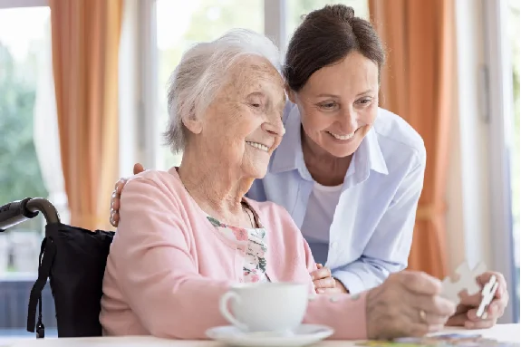 Smiling caregiver supporting an elderly woman at Elite Care Assisted Living Facility in Lakeland, Florida, creating a warm and welcoming environment.